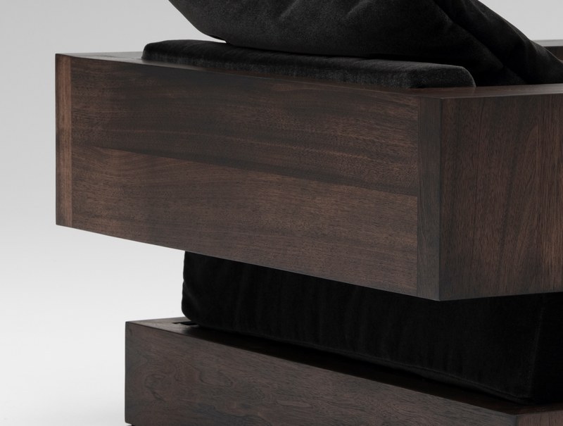 Close-up of dark walnut grain, layered frame construction and black velvet upholstery on a hotel lounge chair
