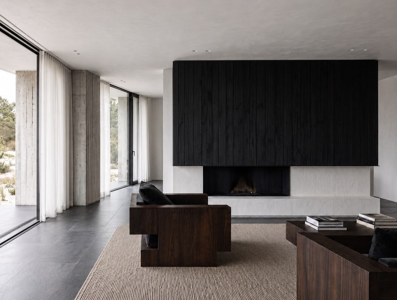 Custom walnut lounge armchair with black velvet cushion in a concrete and glass hospitality lounge interior