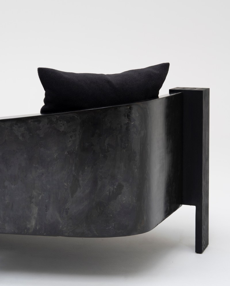 Rear detail of the hotel lounge sofa showing its curved dark-textured shell and square end support