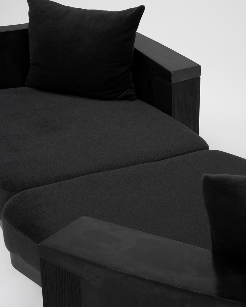 Close-up of the dark wood-grain end support and textured curved surround of the custom hotel sofa