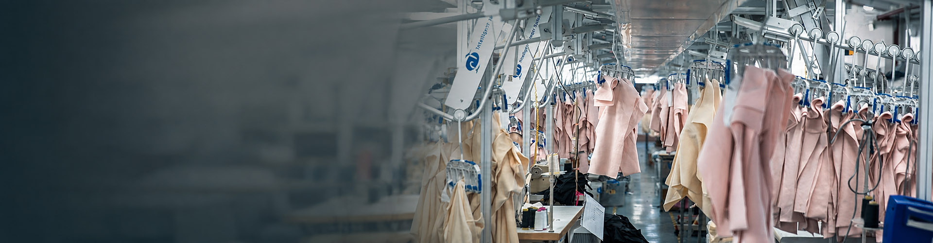 Garment production area with hanging apparel on the factory line, shown in a wide banner layout for MinCharm.