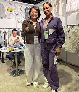 MinCharm representatives meeting a visitor at a Dubai apparel trade show in 2025