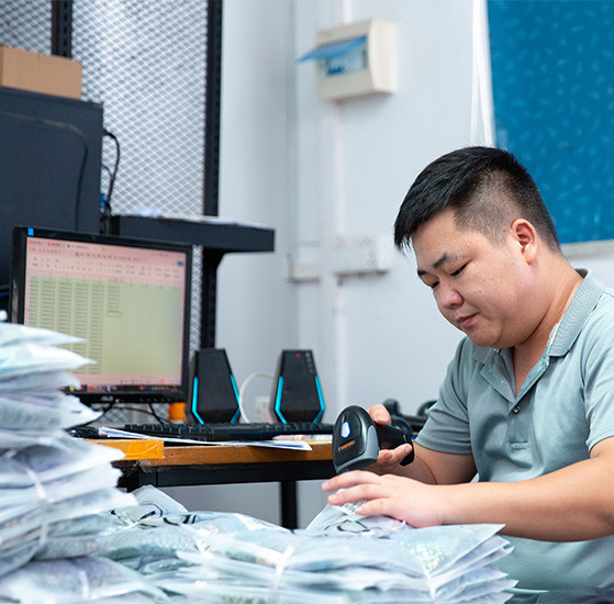 Worker scanning packaged garments during private label order checking at MinCharm