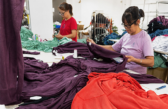 Worker inspecting garment workmanship and construction during quality control