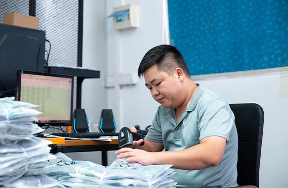 Worker scanning packaged garments during packing and order checking