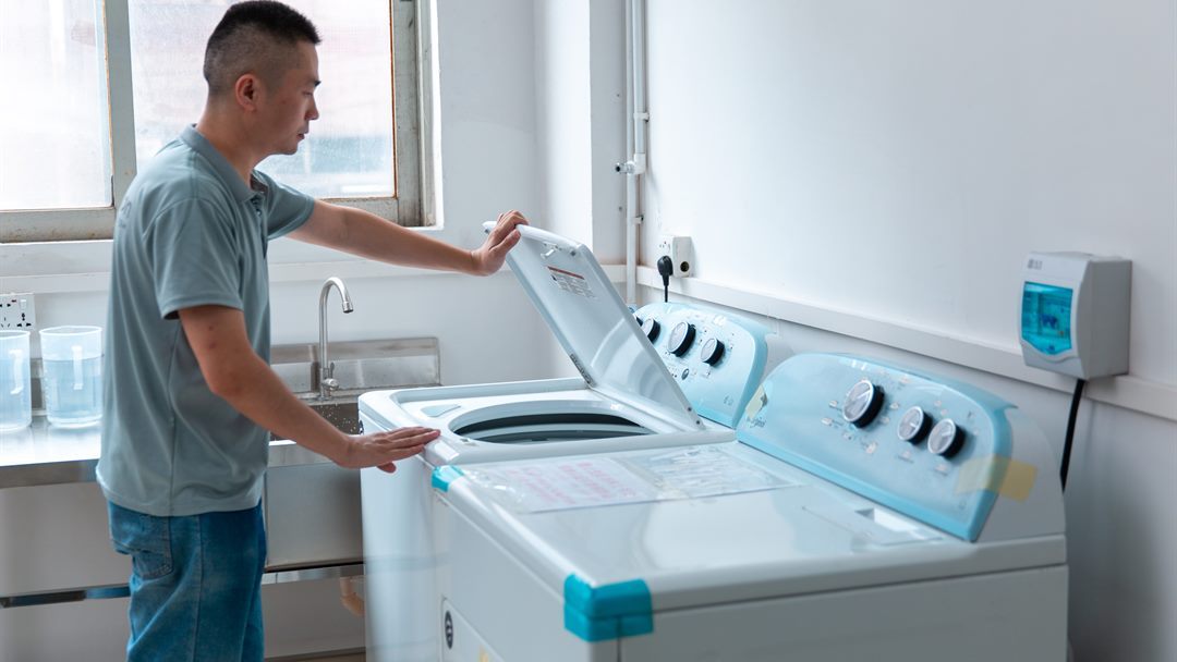 Technician operating washing test equipment while evaluating fabric wash performance