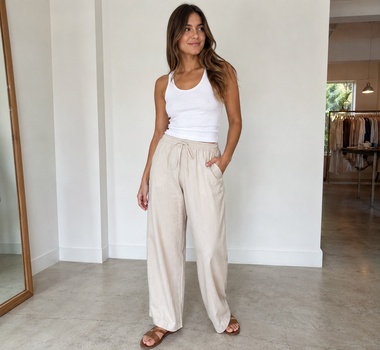 Woman wearing wide-leg beige drawstring lounge pants with a white tank top