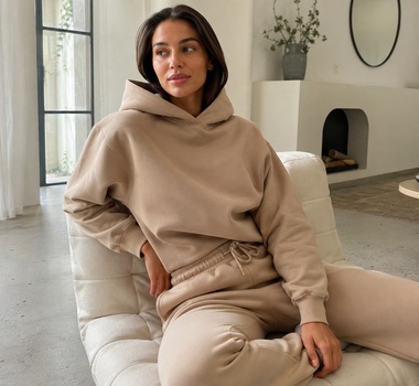 Woman wearing a beige lounge hoodie and matching drawstring sweatpants