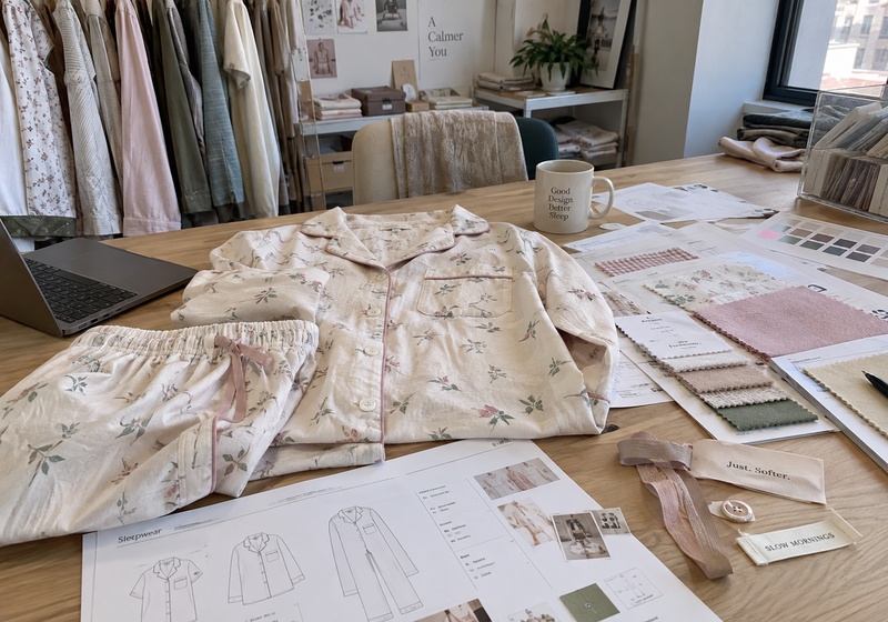 Women’s floral pajama set with fabric swatches and technical drawings on a design table