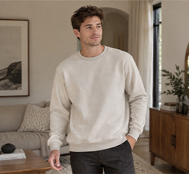 Male model wearing a cream crewneck sweatshirt with a relaxed fit