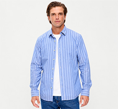 Man wearing a light blue striped button-front shirt over a white T-shirt