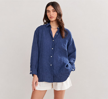 Woman wearing a loose navy button-front shirt with white shorts