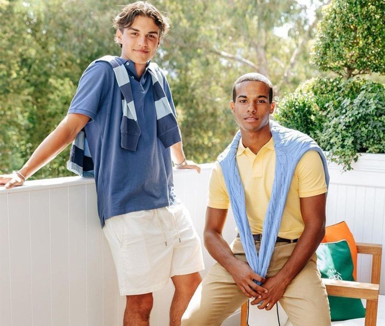 Two men wearing blue and yellow polo shirts outdoors.