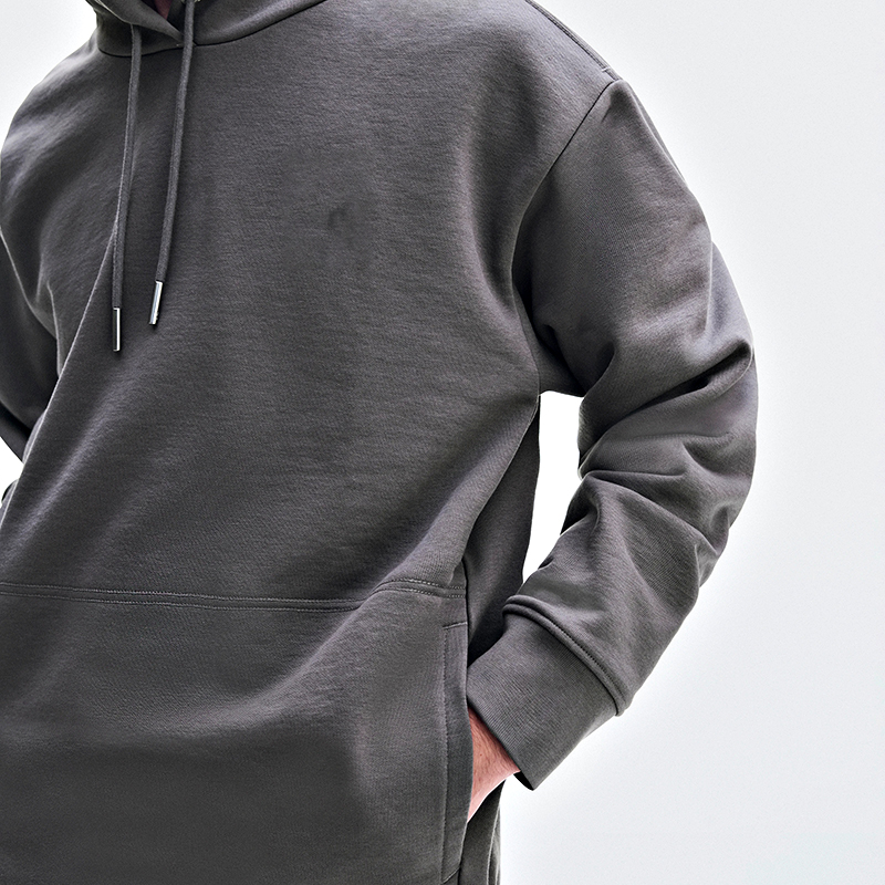 Close-up of the charcoal hoodie chest with metal-tipped drawcords and kangaroo pocket edge