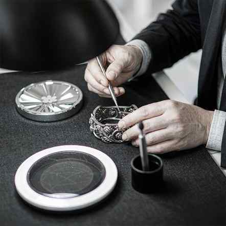 Jeweler setting stones into an ornate 925 silver bracelet at the sample bench