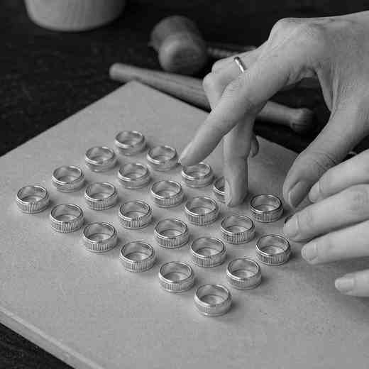 Hands arranging a batch of identical 925 sterling silver rings to illustrate per-style MOQ