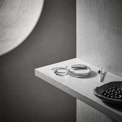 Polished 925 sterling silver rings and a cuff bracelet arranged on a light wooden display shelf