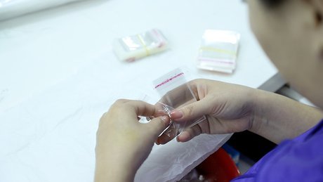 Quality inspector examining a finished silver ring on a white inspection table