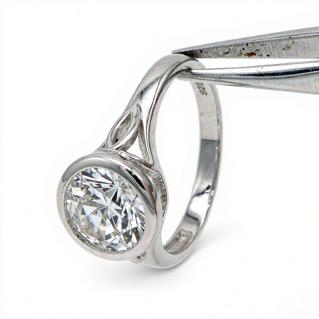 925 sterling silver ring with cubic zirconia held by silver tweezers on a white background