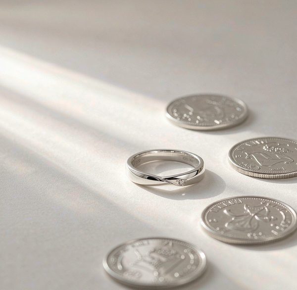 A 925 sterling silver ring beside polished silver coins on a clean white background