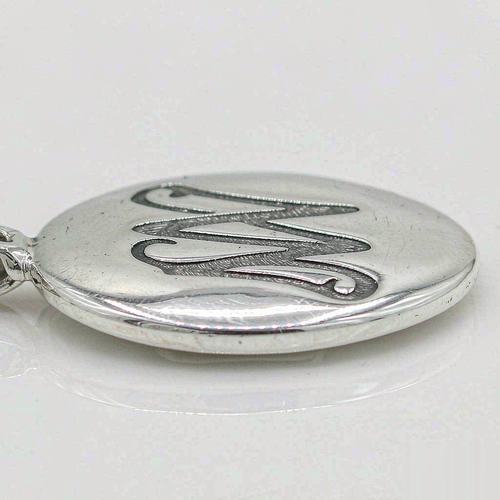 Close-up of the polished back of a 925 sterling silver pendant with an engraved monogram mark