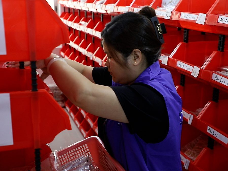 Quality control: a worker sorting components in the storage area of our factory