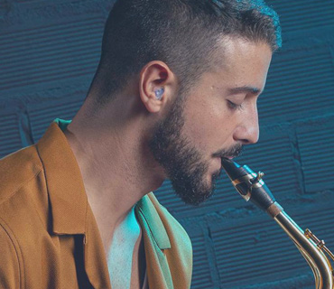 A man playing saxophone with earplugs